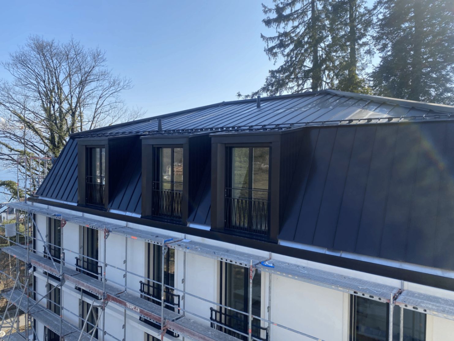 Mehrfamilienhaus mit dunklem Metall-Mansardendach