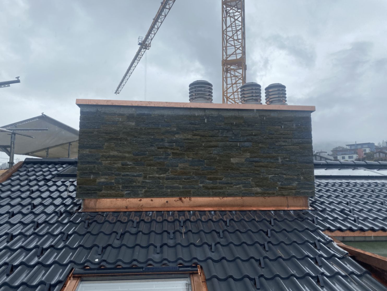 Kamin mit Schieferverkleidung und Kupfereinfassung auf einem Ziegeldach