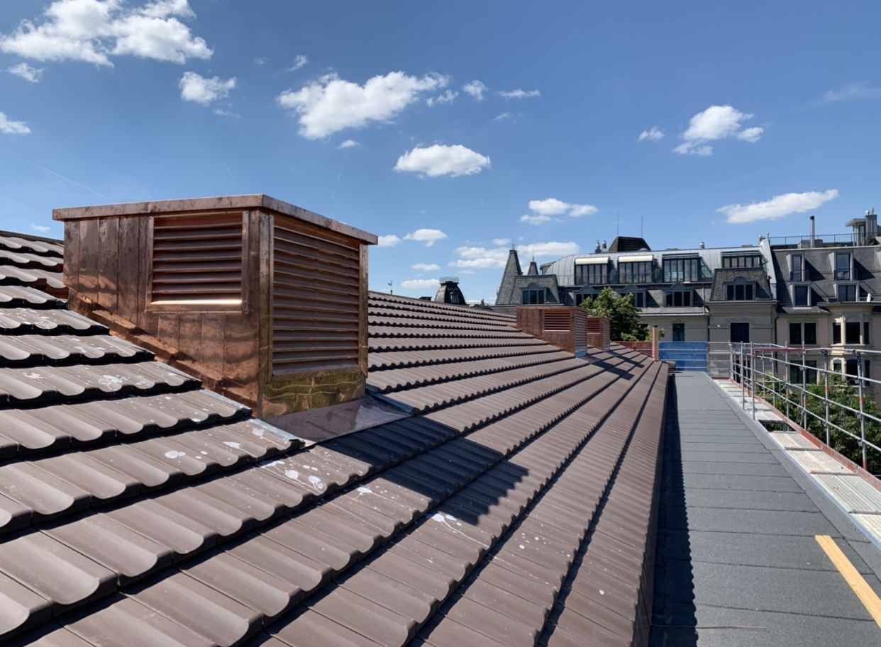 Kupferverkleidete Lüftungsaufbauten auf einem Ziegeldach unter blauem Himmel